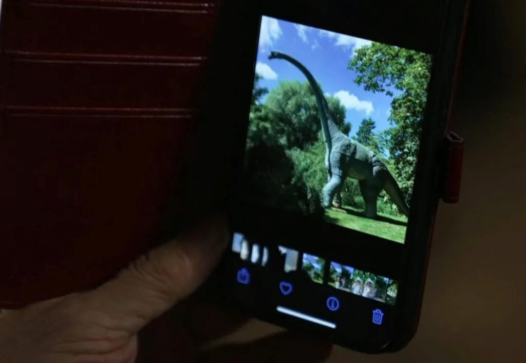 A hand holding a phone with a dinosaur on it

Description automatically generated