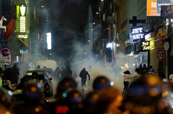 Protesters running down a Paris street as they flee tear gas fired by the police.