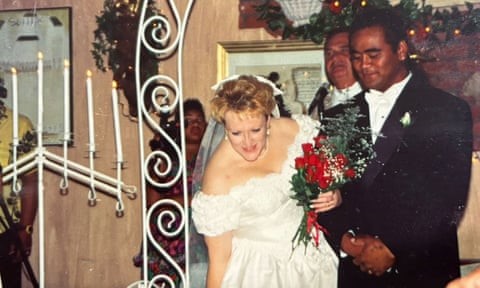 a woman in a white off the shoulder wedding dress with a man in black tie standing next to her