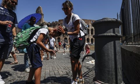 People at a drink fountain in front of the Colosseum in Rome